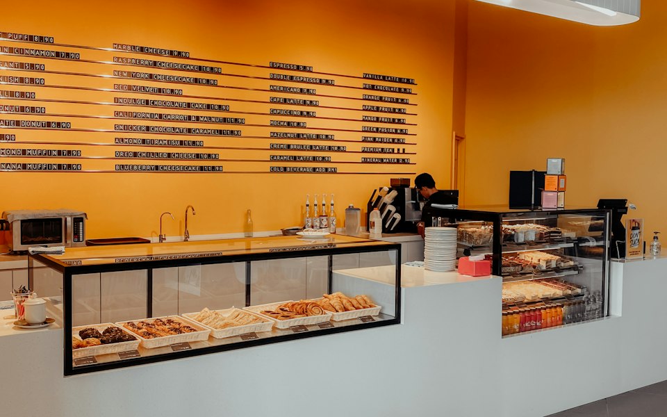 Mostrador de restaurante con vitrina de alimentos y punto de cobro